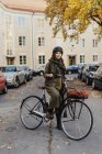 Молода жінка стоїть з велосипедом на вулиці — стокове фото