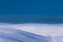 Snow covered hills with distant hikers — Stock Photo