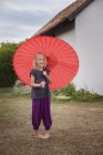 Дівчина з червоним парасолькою, фокус на передньому плані — стокове фото