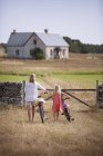 Mother and daughter wheeling bicycles toward farm gate — Stock Photo