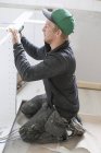 Carpintero en ropa de trabajo protectora instalando muebles - foto de stock
