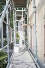 Mann auf Baugerüst befestigt Abstellgleis an Haus — Stockfoto
