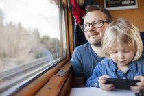 Отец и дочь путешествуют на поезде и смотрят в окно — стоковое фото