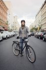 Чоловік стоїть на велосипеді на вулиці, фокус на передньому плані — стокове фото