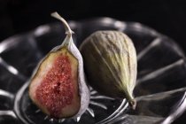 Close up shot of fresh whole and half of figs on plate — Stock Photo