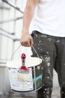 Uomo che trasporta secchio di vernice bianca con pennello — Foto stock