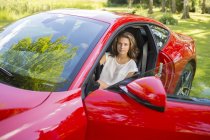 Adolescente sentada no carro vermelho — Fotografia de Stock