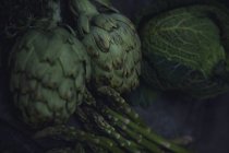 Свіжі зелені артишоки, капуста, спаржа і чебрець на скатертині — стокове фото