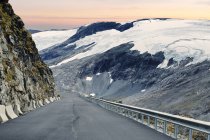 Vue en bas de la route menant le long de la montagne enneigée — Photo de stock