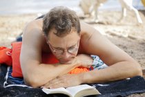 Retrato del hombre leyendo en la playa, enfoque en primer plano - foto de stock