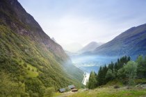 Маленькі будинки зеленими горами з низькими хмарами — стокове фото
