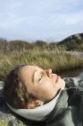 Mulher adulta média dormindo na margem do rio, foco seletivo — Fotografia de Stock