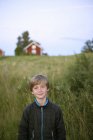Ritratto di ragazzo in piedi sull'erba, messa a fuoco selettiva — Foto stock