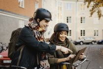 Casal de pé com bicicletas e usando tablet digital, foco seletivo — Fotografia de Stock