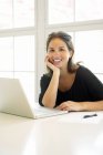 Portrait of young woman with laptop smiling at camera — Stock Photo