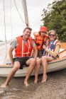 Сім'я з дитиною в рятувальних жилетах на вітрильному човні — стокове фото