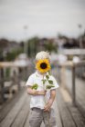 Boy holding sunflower, focus on foreground — Stock Photo