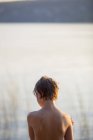 Visão traseira do menino em pé junto ao lago — Fotografia de Stock