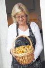Старшая женщина держит в руках трюг, наполненный грибами с кантереллой — стоковое фото