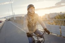 Homme à vélo sur le pont au coucher du soleil, mise au point sélective — Photo de stock