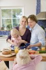 Família com duas crianças tomando café da manhã de cereais e suco de laranja — Fotografia de Stock