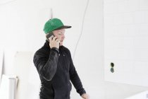 Carpenter talking on mobile phone at house interior — Stock Photo