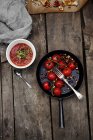 Frying pan with tomatoes and ketchup on wooden table — Stock Photo