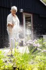 Sênior mulher regando flores no jardim — Fotografia de Stock