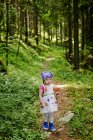 Porträt eines Mädchens mit Puppe, das im Wald in die Kamera blickt — Stockfoto