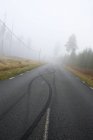 Vista di strada vuota con tracce di pneumatici coperti di nebbia — Foto stock