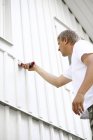 Baixo ângulo de visão da parede homem pintura com escova — Fotografia de Stock