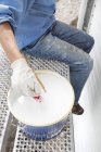 Low section of senior man putting paintbrush into bucket — Stock Photo