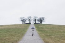 Rear view of woman with umbrella at Woodland Cemetery — Stock Photo