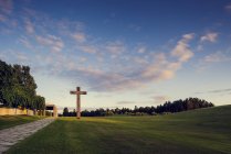 Entferntes Kreuz auf grünem Feld unter blauem bewölkten Himmel — Stockfoto