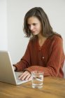 Jovem mulher usando laptop na mesa — Fotografia de Stock