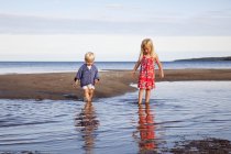 Menino e menina brincando na água na praia — Fotografia de Stock
