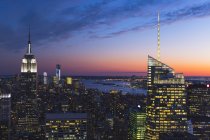 Rascacielos iluminados de Manhattan bajo cielo nublado al atardecer - foto de stock