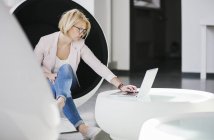 Mulher usando laptop na cadeira de bola, foco diferencial — Fotografia de Stock