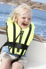 Девушка сидит в лодке в спасательной куртке и веселится — стоковое фото