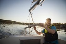 Mature man sailing at sunset, lens flare — Stock Photo