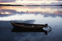 Barca ormeggiata sull'acqua di mare con riflesso del cielo nuvoloso al tramonto — Foto stock