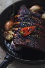 Close-up of black frying pan with spareribs — Stock Photo