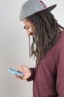 Портрет молодого чоловіка в дредлоках за допомогою смартфона — стокове фото