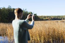 Вид ззаду жінки, фотографує водно-болотні угіддя — стокове фото