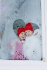 Sisters looking out frosted window, selective focus — Stock Photo