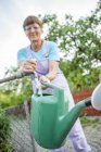 Woman filling watering can in garden — Stock Photo
