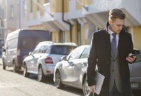 Businessman texting at street, focus on foreground — Stock Photo