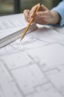 Female hand holding pencil over blueprint — Stock Photo