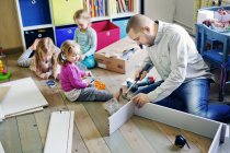 Father building cabinet for daughters in nursery — Stock Photo