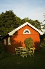 Falu casa de campo vermelha com mesa e cadeiras à luz do sol — Fotografia de Stock